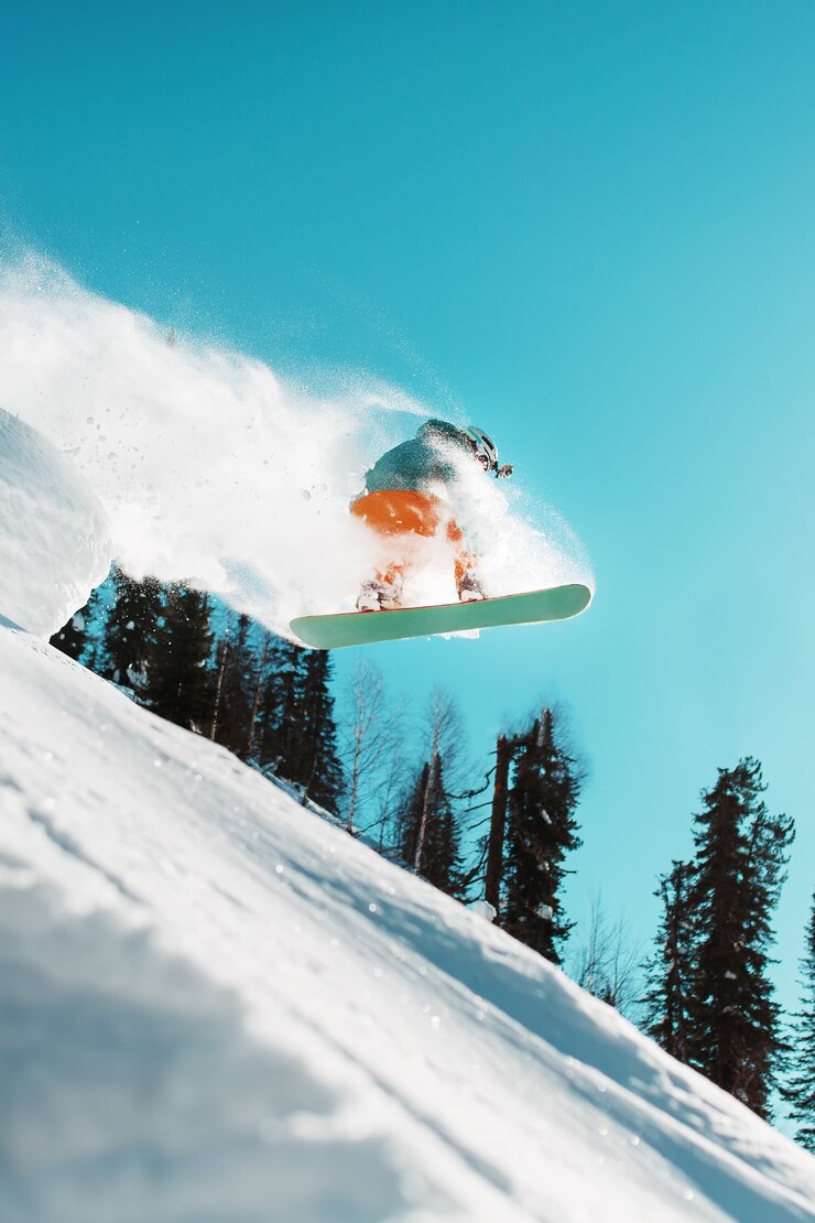 Foto ein snowboarder springt von einem hohen schneebedeckten sprungbrett in einem wald gegen einen blauen himmel. extremsportarten