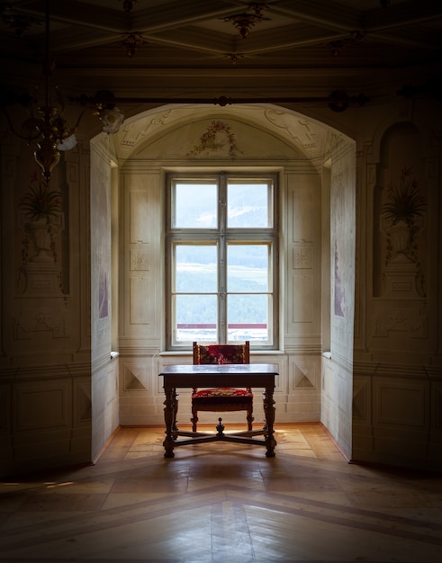 Ein Solitärstuhl und ein Tisch in einem geräumigen Raum des Schlosses Savoia, Gebäude im typischen Walsen-Baustil.