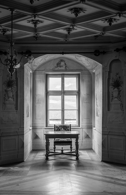 Ein Solitärstuhl und ein Tisch in einem geräumigen Raum des Schlosses Savoia, Gebäude im typischen Walsen-Baustil.