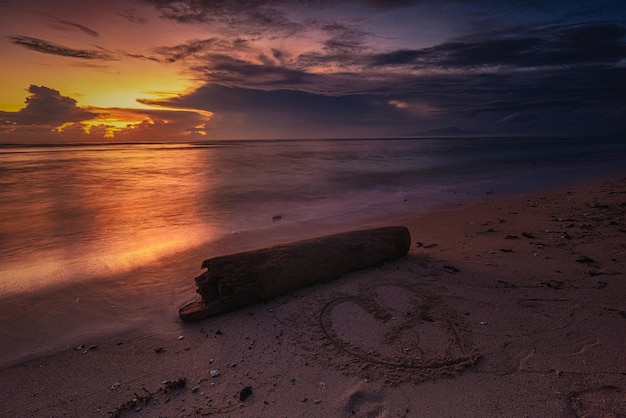 Ein Sonnenuntergang mit einem in den Sand gezeichneten Herzen