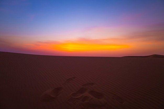 ein Sonnenuntergang mit Fußabdrücken in den Sanddünen