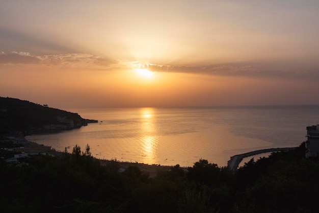 Ein Sonnenuntergang über dem Meer, hinter dem die Sonne untergeht. Die felsige Küste der Adria