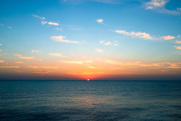 Ein Sonnenuntergang über dem Meer mit orangefarbenen Sonnenstrahlen, die durch das Meer verschwinden