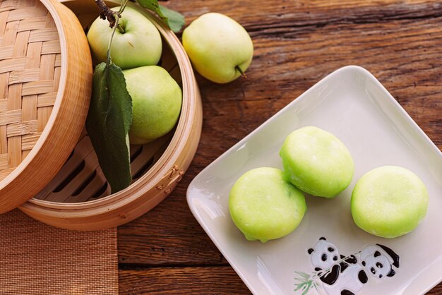 Foto ein speiseplatt mit grünen äpfeln neben einem korb mit äpflchen auf einem holztisch mochi asiatisches dessert