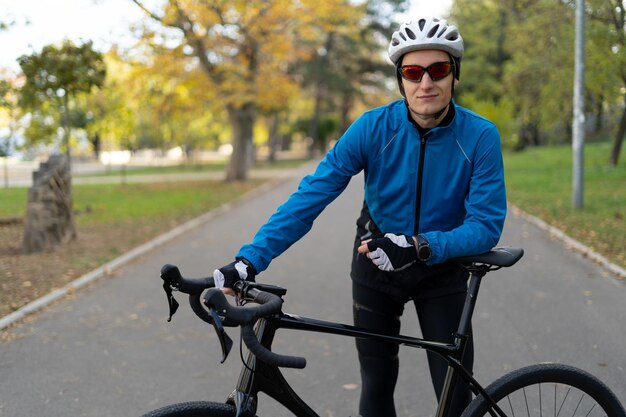 Ein Sportler mit Brille und Fahrradschutzhelm steht im Park auf einer Fahrradstraße. Sport und Erholung im Freien.