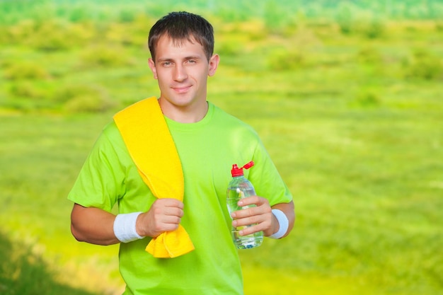 Ein Sportler mit Handtuch, der eine Flasche Wasser hält