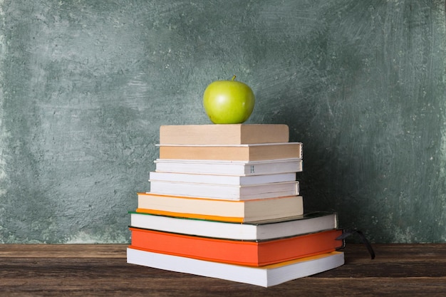 Ein Stapel Bücher und ein grüner Apfel auf dem Hintergrund der Schulbehörde. Bildung und zurück zum Schulkonzept.