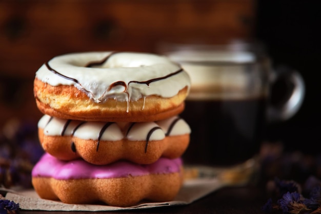 Ein Stapel Donuts mit weißem Zuckerguss und ein Glas Kaffee.