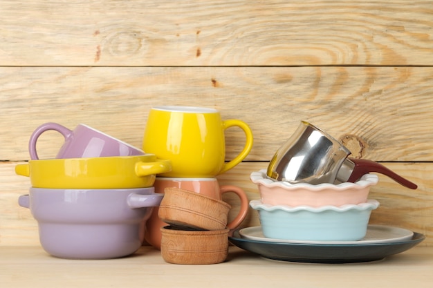 Ein Stapel Geschirr. farbiges Geschirr auf einem natürlichen Holztisch. mehrfarbige Tassen und Schalen.