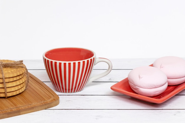 Ein Stapel knuspriger Kekse auf dem Hintergrund süßer Marshmallows und einer Keramiktasse Süßes Frühstück