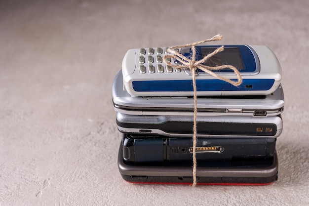 Ein Stapel Mobiltelefone, die mit Bindfaden auf grauem Putz zusammengebunden sind