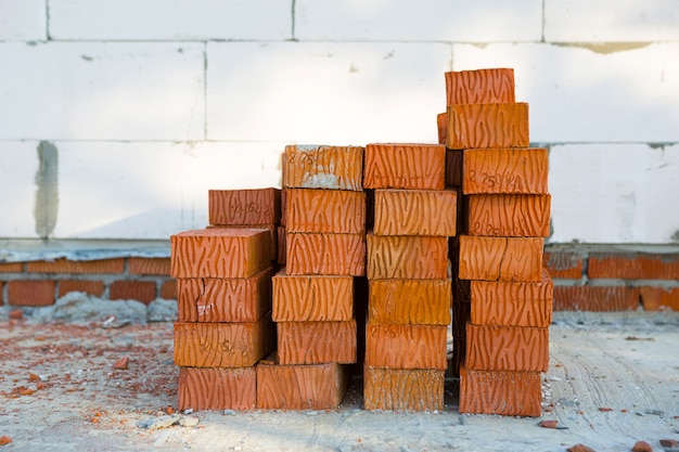 Ein Stapel roter Ziegelsteine auf einer Baustelle. Baumaterialien, Lieferung, Lager. Platz kopieren