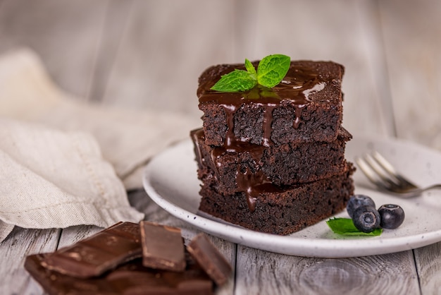 Ein Stapel Schokoladenbrownies auf Holzoberfläche mit Minzblatt oben, hausgemachte Bäckerei und Dessert