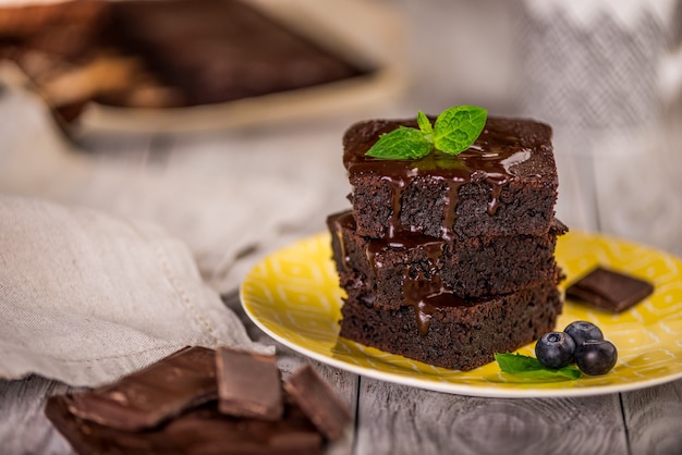 Ein Stapel Schokoladenbrownies auf Holzoberfläche mit Minzblatt oben, hausgemachte Bäckerei und Dessert