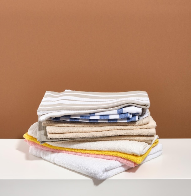 Ein Stapel verschiedener sauberer Handtücher auf einem weißen Tisch. Frisch gewaschene Wäsche