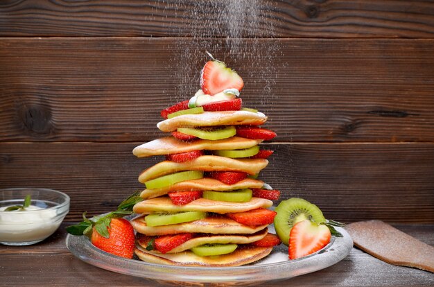 Ein Stapel Weihnachtsbaumpfannkuchen und tropfender Puderzucker auf dunklem Holzhintergrund