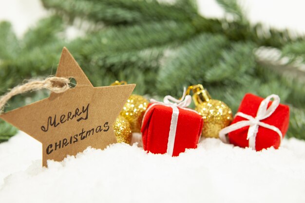 Ein Stern mit der Aufschrift frohen Weihnachten und Geschenken mit Bällen auf weißem Schnee
