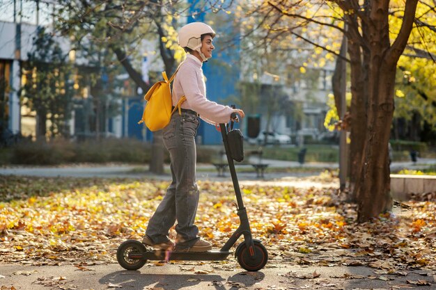 Ein stilvolles Mädchen fährt auf einer Straße einen elektrischen Roller