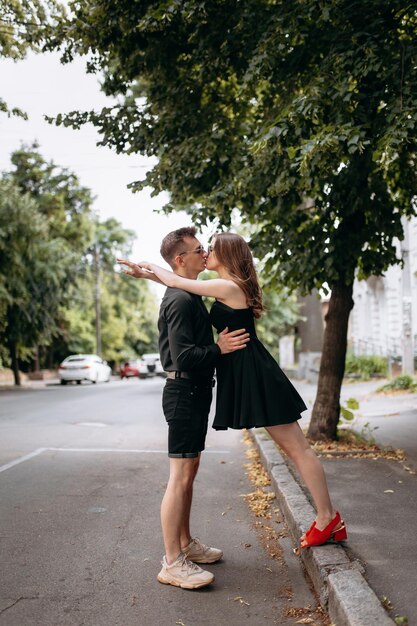 Ein stilvolles verliebtes Paar in schwarzer Kleidung geht auf der Straße und lacht