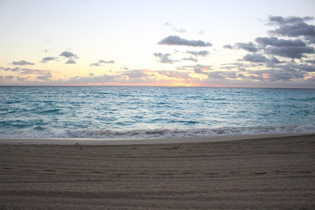 Ein Strand mit blauem Meer und ein Strand mit einem Sonnenuntergang im Hintergrund.