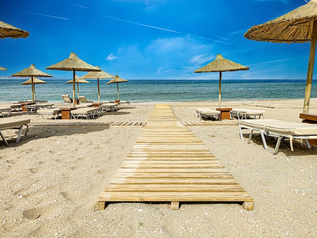 Ein Strand mit einem Holzsteg und Sonnenschirmen darauf