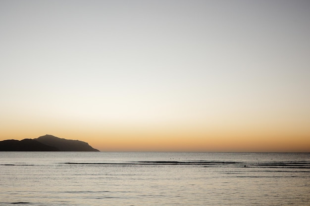 Ein Strand mit einem Sonnenuntergang und einer Person, die im Wasser steht