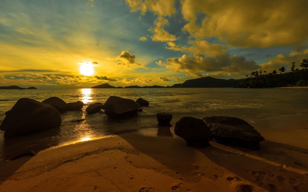 Ein Strand mit Sonnenuntergang und dahinter die untergehende Sonne
