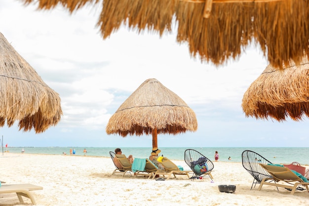 Ein Strand mit Stühlen und strohgedeckten Sonnenschirmen
