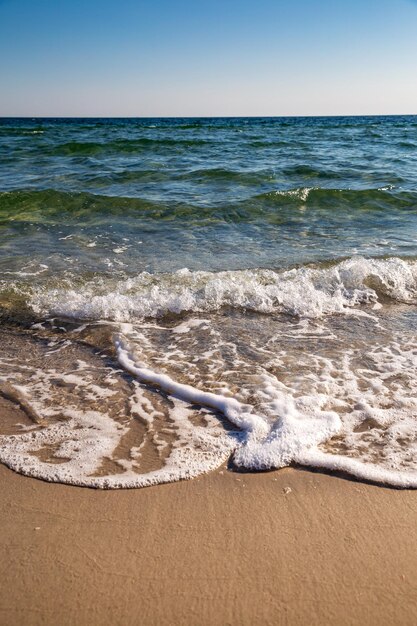 Ein Strand mit Wellen und dem Meer im Hintergrund