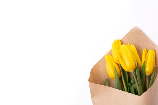 Ein Strauß Frühlingstulpen mit gelben Blumen, eingewickelt in Kraftpapier für ein Geschenk, isoliert auf weißem Hintergrund