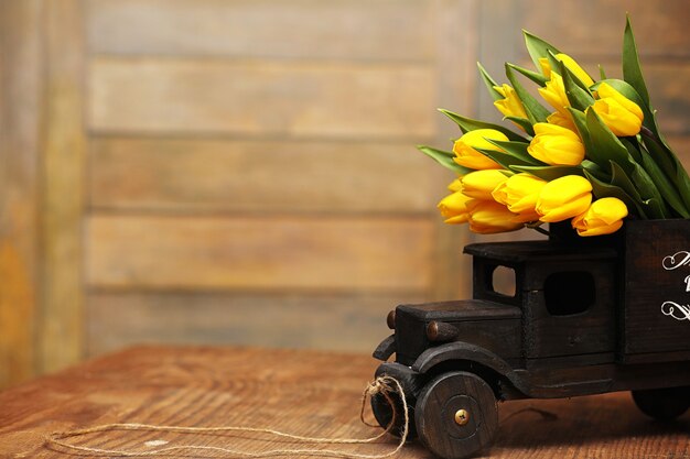 Ein Strauß gelber Tulpen in einer Vase auf dem Boden. Ein Geschenk zum Tag einer Frau aus gelben Tulpenblumen. Schöne gelbe Blumen in einer Vase an der Wand.