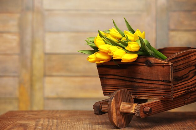 Ein Strauß gelber Tulpen in einer Vase auf dem Boden. Ein Geschenk zum Tag einer Frau aus gelben Tulpenblumen. Schöne gelbe Blumen in einer Vase an der Wand.