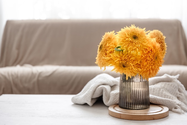 Ein Strauß heller Sonnenblumen in einer Glasvase auf unscharfem Hintergrund im Inneren des Raumes, Kopierraum.