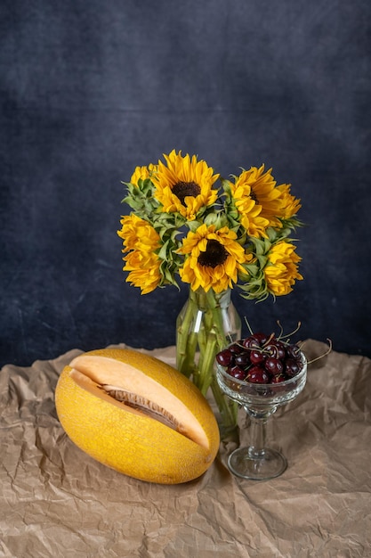 Ein Strauß Herbstsonnenblumen in einer Glasvase auf Bastelpapier. Melonen- und hohe Kirschvase