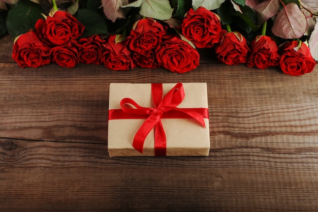 Ein Strauß roter Rosen, ein Geschenk auf Holztisch