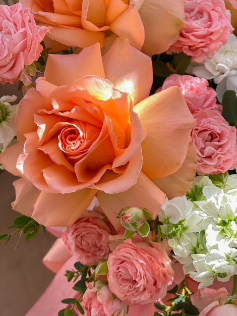 Ein Strauß schöner Pfirsichblumen in einer Schachtel steht auf einem Stuhl in einem Blumenladen. Eine Komposition aus Rosen, weißer Mattiola und Chrysantheme. Ein sanftes Geschenk für einen Urlaub