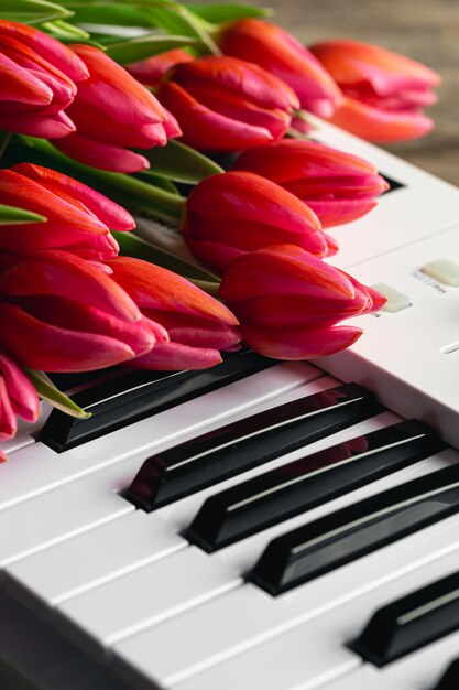 Ein Strauß wunderschöner rosa Tulpen auf den Klaviertasten, Frühlingskonzept-Musikhintergrund