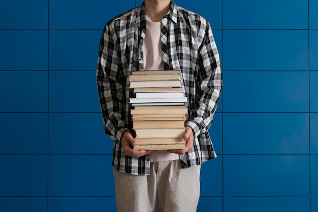 Ein Student, der einen Stapel Bücher hält und trägt