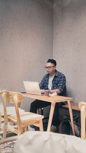 Ein Student, der mit seinem Laptop an einer Aufgabe arbeitet, begleitet von einer Tasse Kaffee