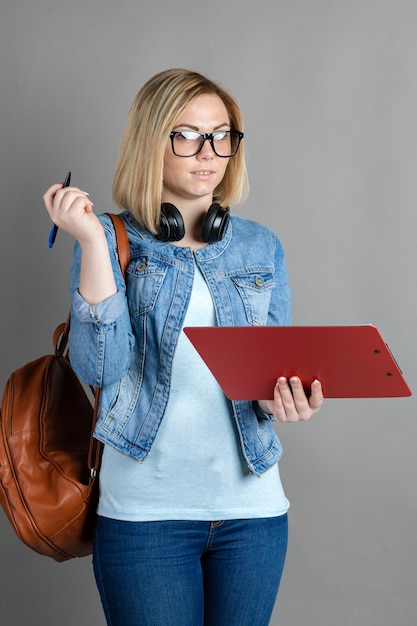 Ein Student mit einem Ordner zum Schreiben auf grauem Hintergrund