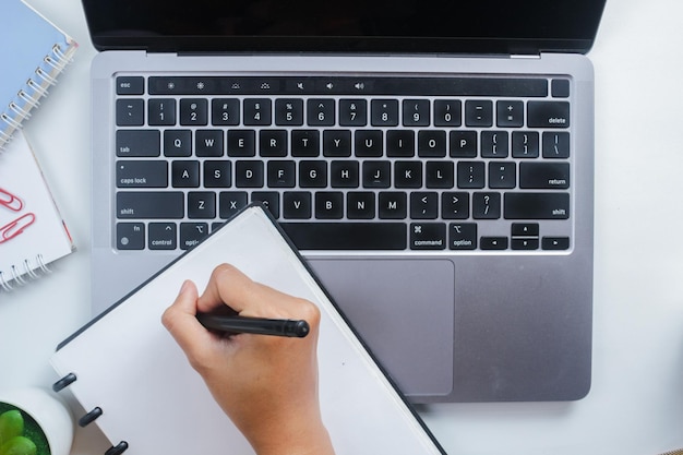 Foto ein studentischer mitarbeiter schreibt auf der tastatur notizen in ein buch