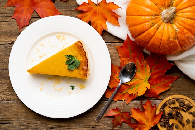 Ein Stück amerikanischer Kürbiskuchen auf einem weißen Teller und einem Holztisch, Herbst flach.
