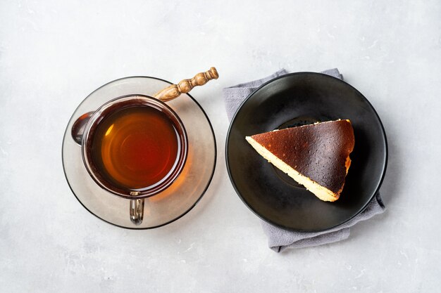 Ein Stück baskisch gebrannter Käsekuchen mit einer Tasse schwarzem Tee