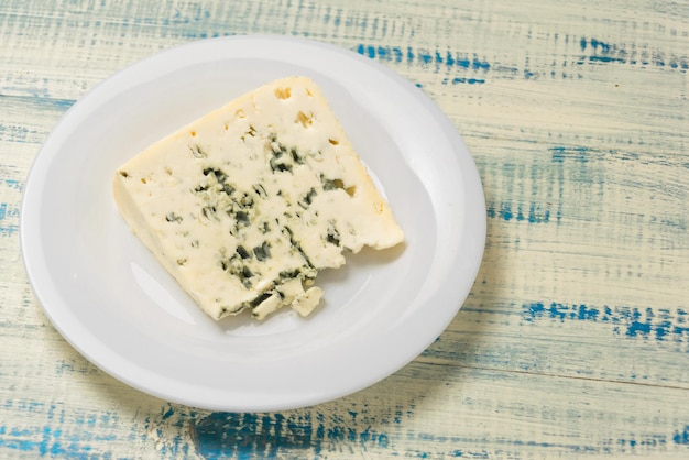 Ein Stück Blauschimmelkäse auf einem Teller auf Holzhintergrund