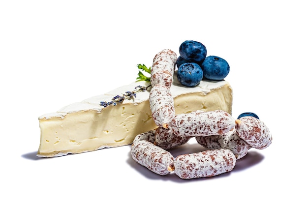 Ein Stück Camembert-Käse mit Blaubeeren und Würstchen mit Schimmel isoliert auf weißem Hintergrund