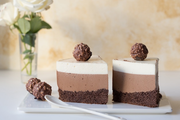 Ein Stück eines Mousse-Kuchens "Drei Schokolade", bestreut mit geriebener Schokolade und dekorierten Süßigkeiten