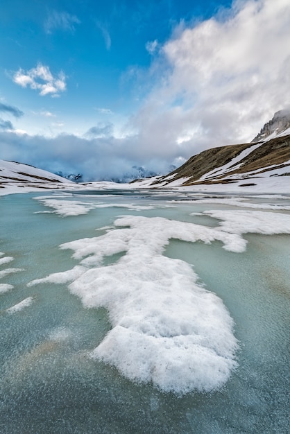 Ein Stück Eis schwimmt in einem zugefrorenen See in den Alpen