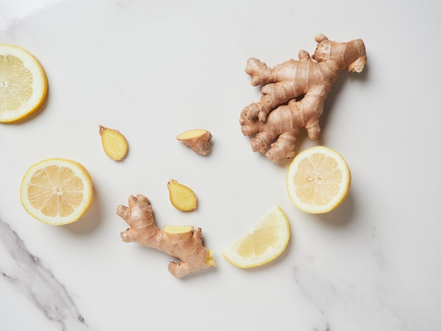 Ein Stück ganze und geschnittene Ingwerwurzel mit Zitronenscheiben auf der Marmorplatte. Antioxidans und heilende gesunde Inhaltsstoffe mit Vitaminen. Ansicht von oben