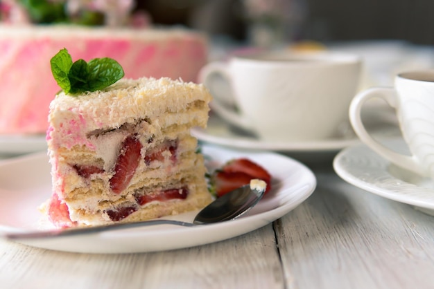 Ein Stück gebackener Kuchen mit Beeren und Sahne auf einem Teller auf weißem Holzhintergrund