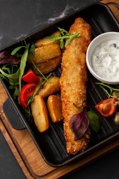 Ein Stück gebackener Lachs, gegrillte Zitrone und Salz auf einem dunklen Teller mit Kartoffelmarmorhintergrund